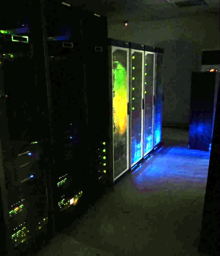 A dark data centre aisle lit by equipment lights