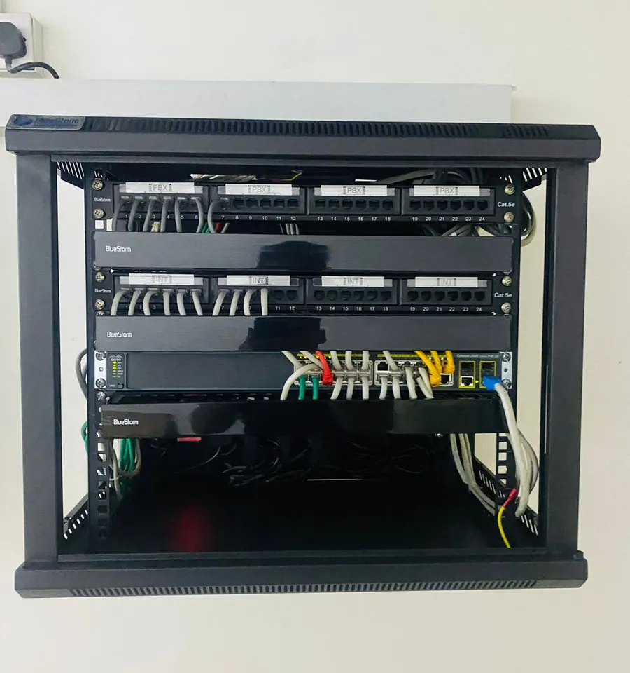 Open wall rack with a Cisco switch and labelled patch panels